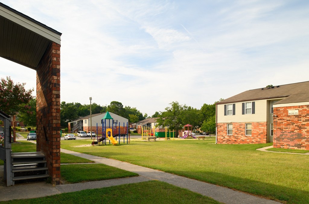 a yard with a playground and houses in the background