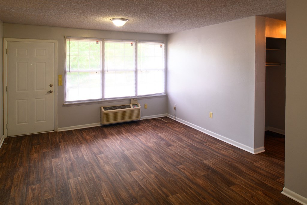 an empty living room with wood floors and a window