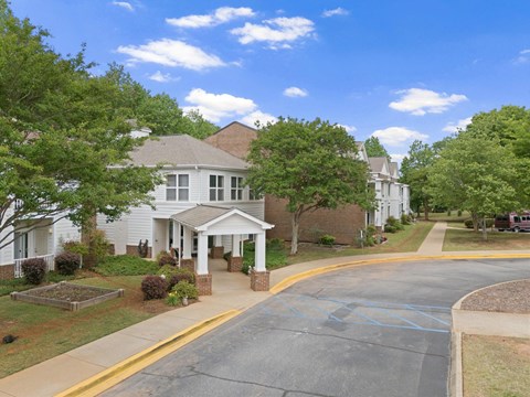 A white house with a porch and a driveway in front.