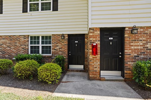 A house with two black doors and a red fire hydrant.