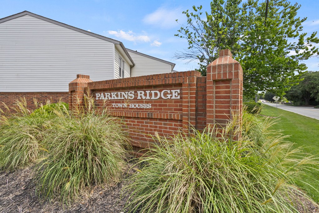 A brick sign that says Parkins Ridge in front of a building.