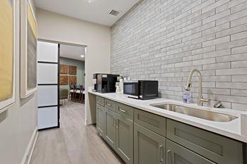 A kitchen with a white sink and green cabinets.