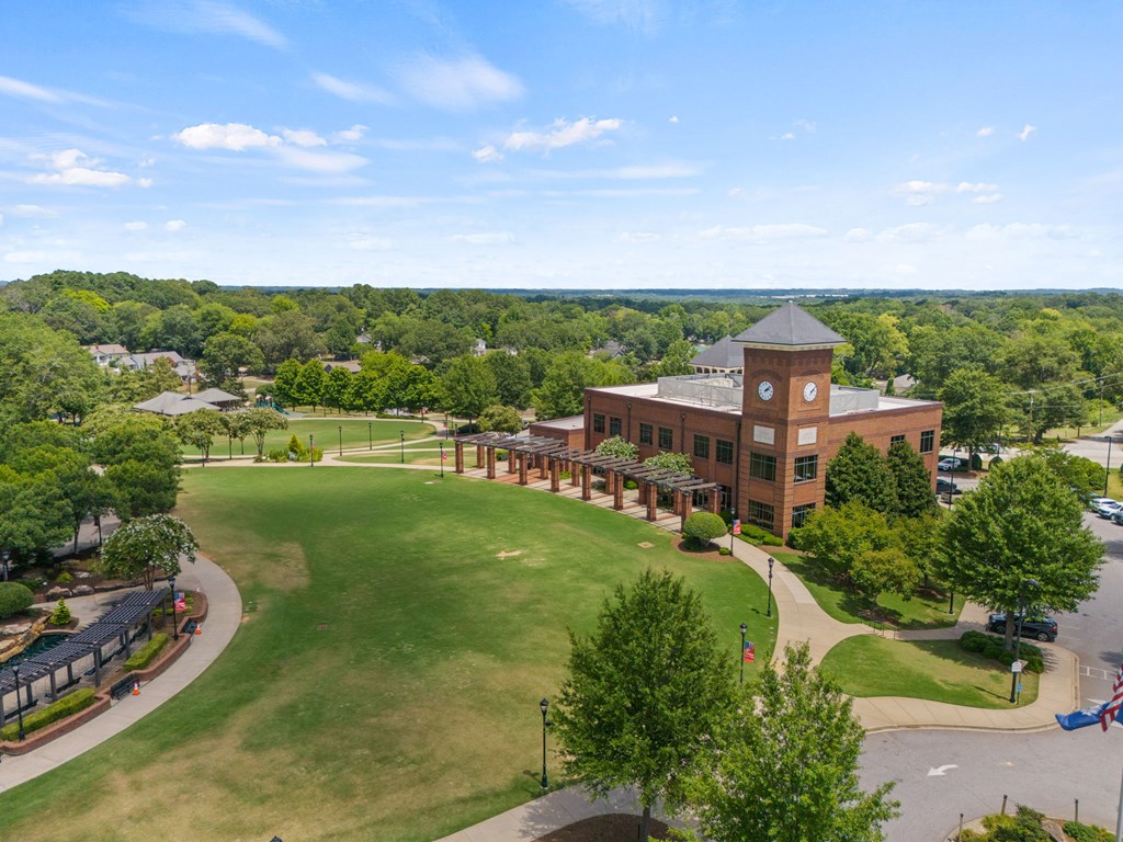 A large building with a clock tower sits in the middle of a green field.
