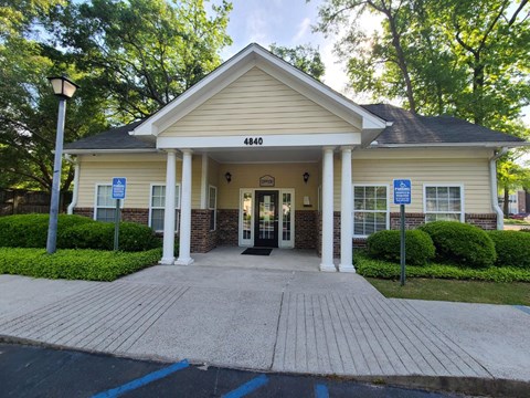 the front entrance of a cream colored building with pillars and a porch