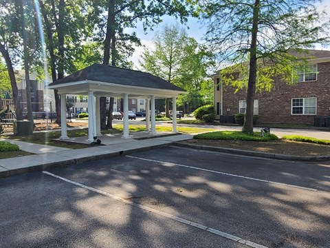 A gazebo is situated in the middle of a parking lot.