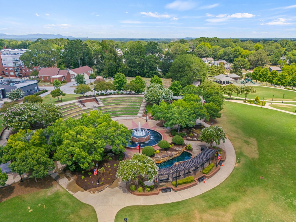 A large green park with a fountain and seating area.
