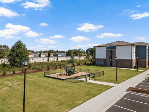 A park with a playground and a building in the background.