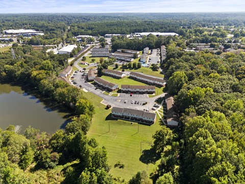 A bird's eye view of a campus with a lake and greenery.