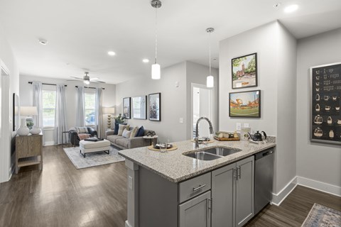 A modern kitchen with a large island and a living area with a couch and chairs.