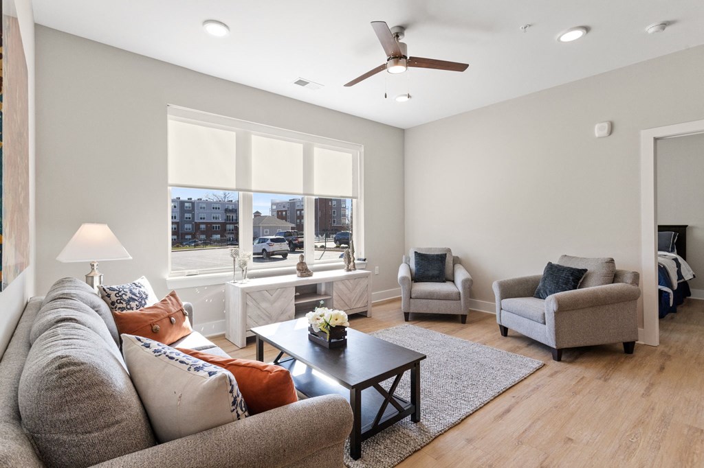 Living room of model unit in Park View Greer Apartments in Greer, SC with a couch, coffee table, two loveseats, three windows and LVT flooring.