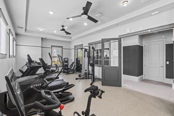 A gym with a variety of exercise equipment including treadmills, stationary bikes, and weight machines.
