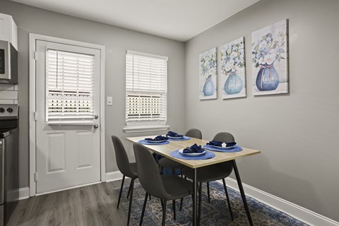 A dining room with a table set for two and two vases on the wall.
