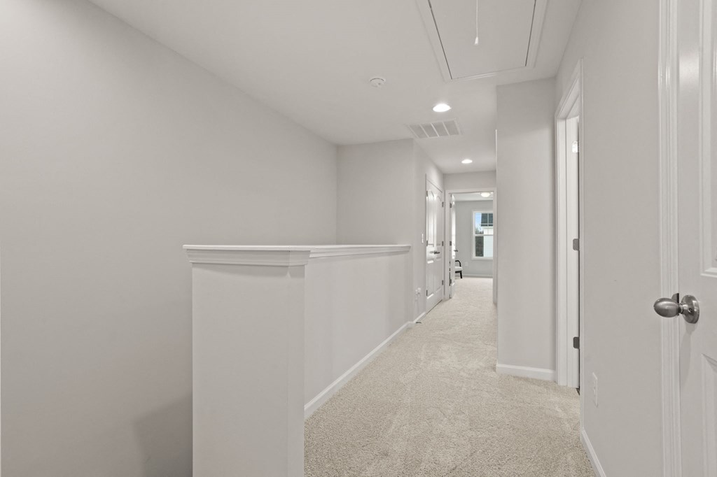 a long white hallway with white walls and white flooring and a white door