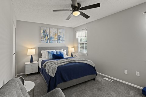 A bedroom with a bed, nightstand, and ceiling fan.