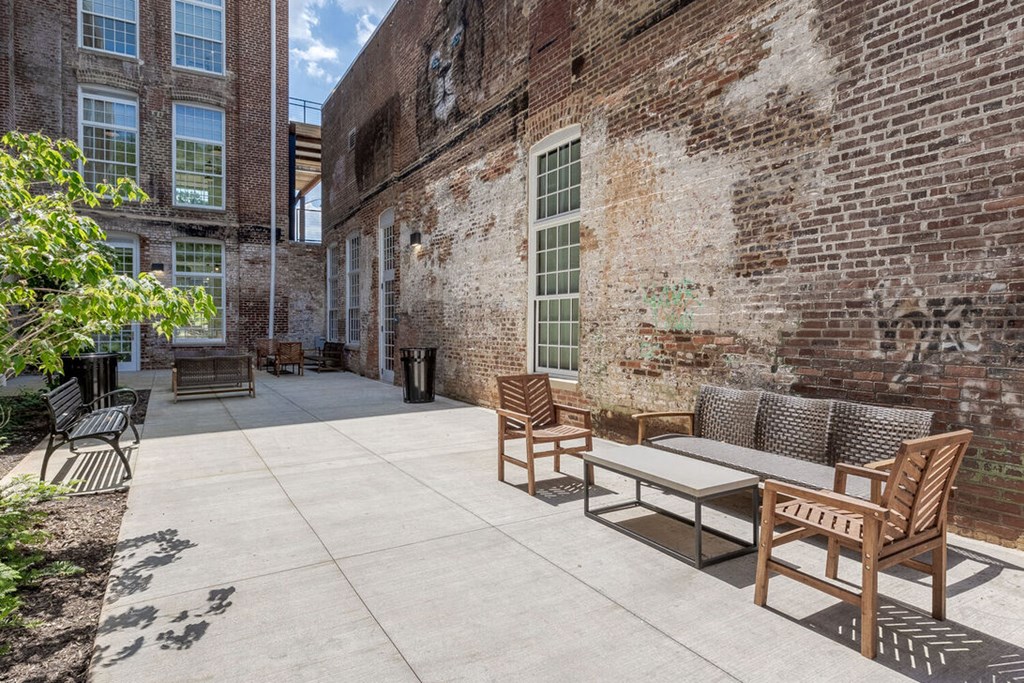 Newry Mill outdoor community patio. Outdoor couches, benches and chairs are pictured along with trashcans.