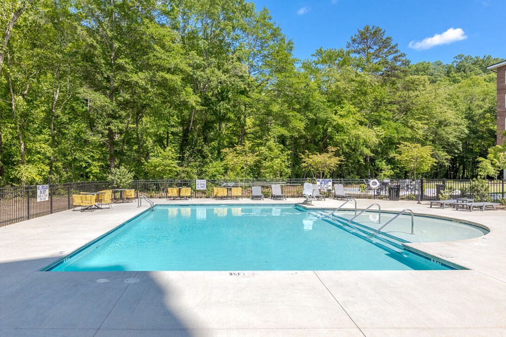 a swimming pool with a fence around it and trees in the background