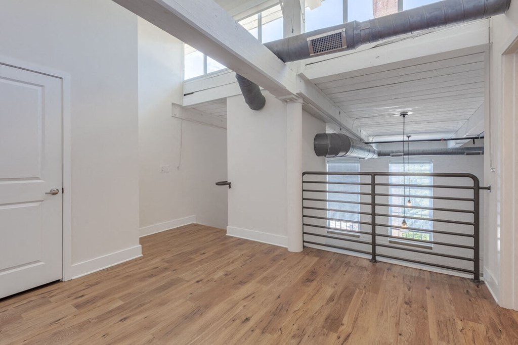 a living room with wood floors and a door to a loft