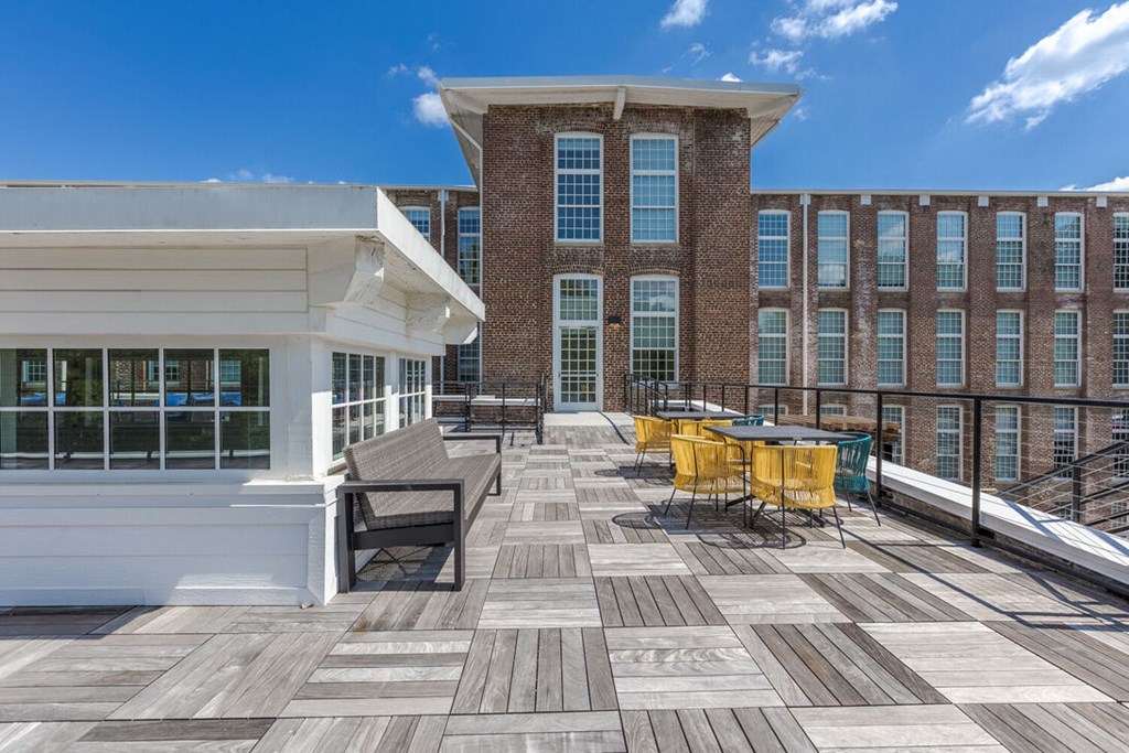 a large deck with tables and chairs in front of a building