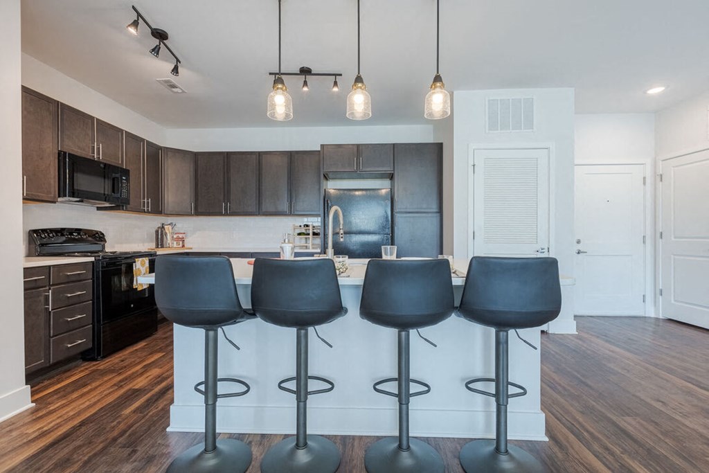 Newry Mill apartments- kitchen with stainless steel appliances including microwave, stove, refrigerator and oven. There is also an island with four barstools in the photo (barstools not included).