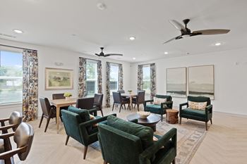 A living room with green chairs and a ceiling fan.
