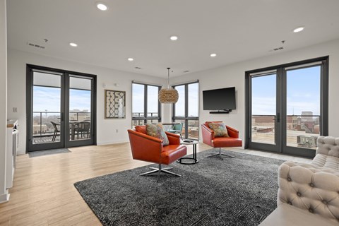 A modern living room with a black rug and red chairs.