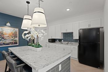 A kitchen with a black refrigerator and a table with a vase of flowers on it.