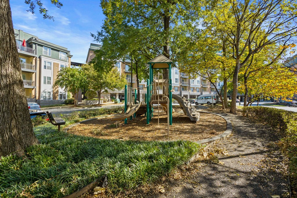 Flatiron West Trade Apartments playground with slides, mulch and a bench.
