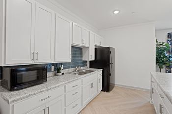 A kitchen with white cabinets and a black refrigerator.