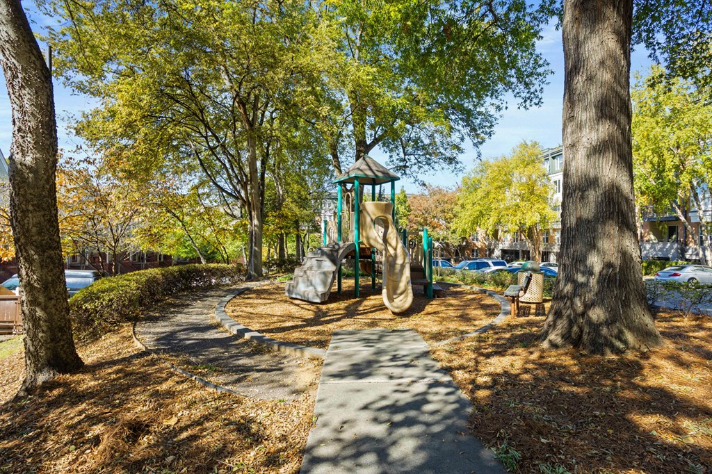 Flatiron West Trade Apartments playground with slides, mulch and a bench.