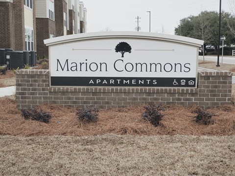 A sign for Marion Commons Apartments is displayed in front of a building.