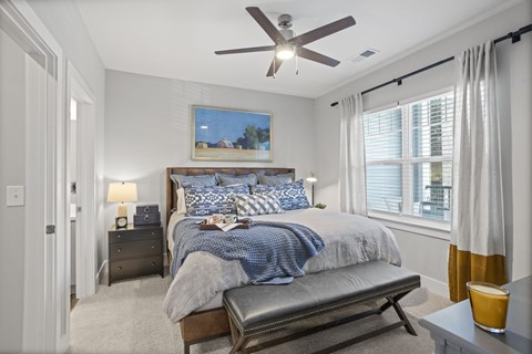 A bedroom with a bed, nightstand, and a ceiling fan.