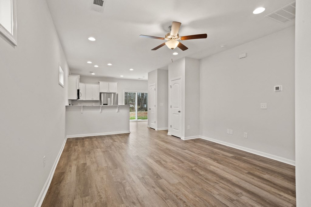 a living room with white walls and a ceiling fan