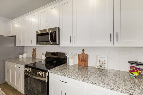 A kitchen with white cabinets and a granite countertop.