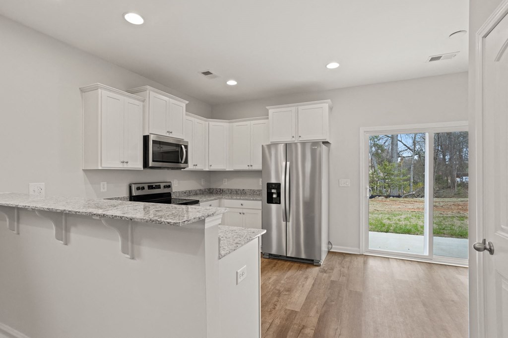a kitchen with white cabinets and a stainless steel refrigerator