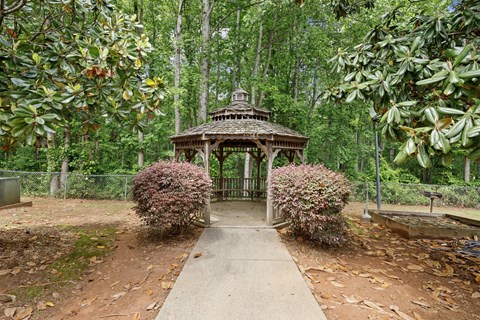 A gazebo is surrounded by green trees and shrubbery.