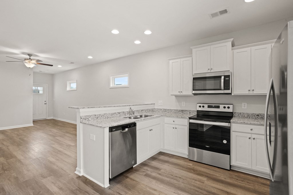 a renovated kitchen with white cabinets and stainless steel appliances