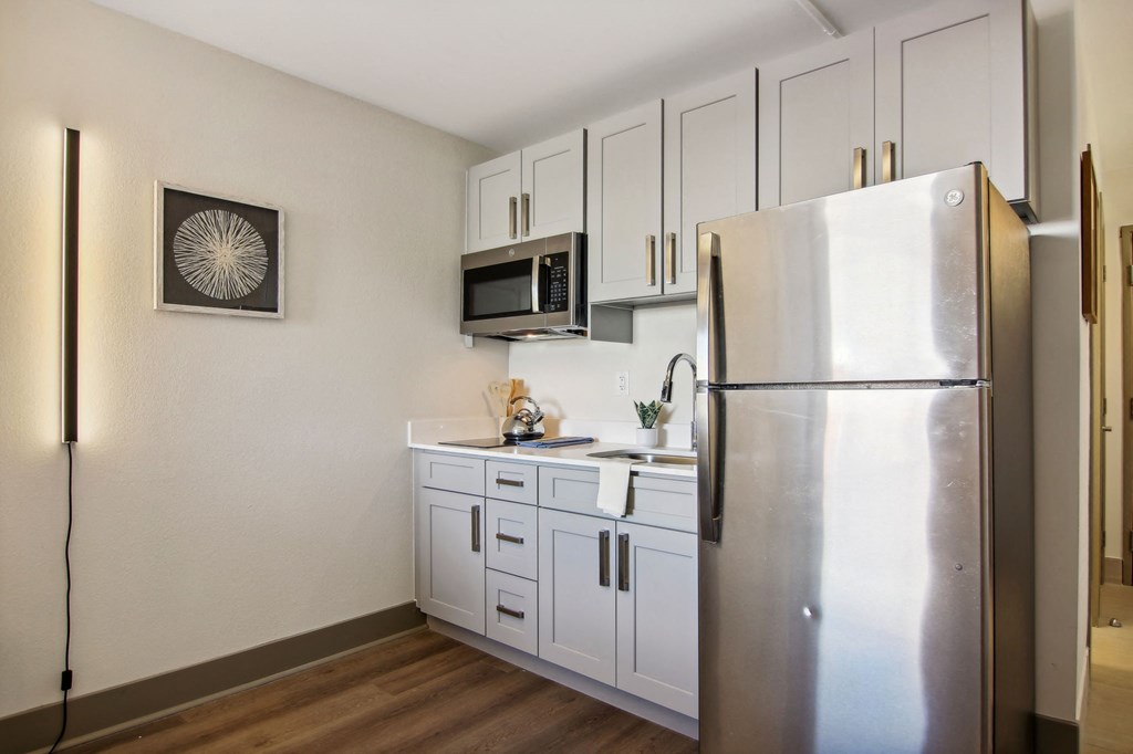 Greenville, SC Apartments | Flathouse Studios | Kitchen with Stainless-Steel Appliances, Quartz Countertops, Integrated Cooktop, and White Cabinetry.