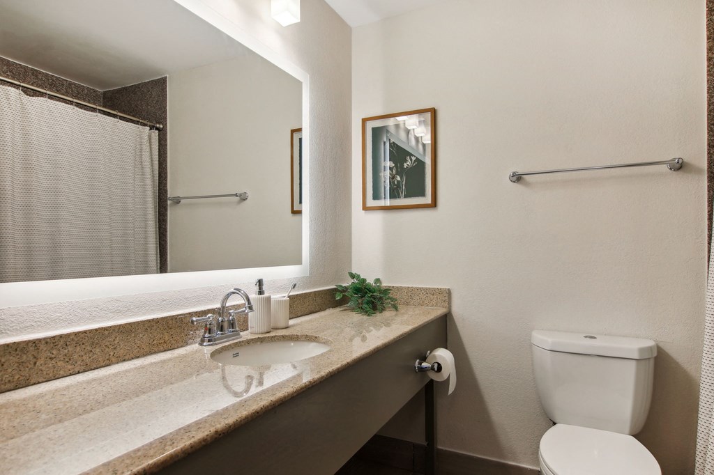 Furnished Studio Apartments | Flathouse Studios | Bathroom with Quartz Countertop, Undermount Sink, and Large Backlit Mirror.