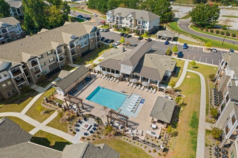An aerial view of apartment buildings with a pool in the foreground.
