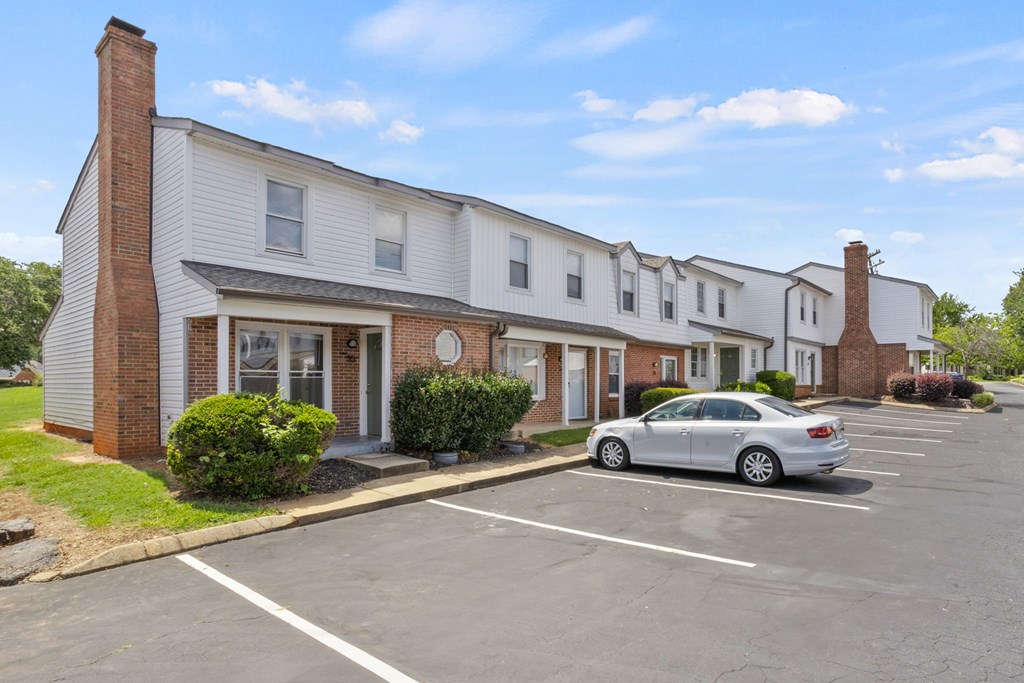 A silver car is parked in a parking lot in front of a building.