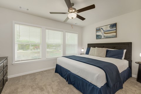 Bedroom with ceiling fan and large windows at The Courts at Maverick Yards Apartments, Mauldin, SC
