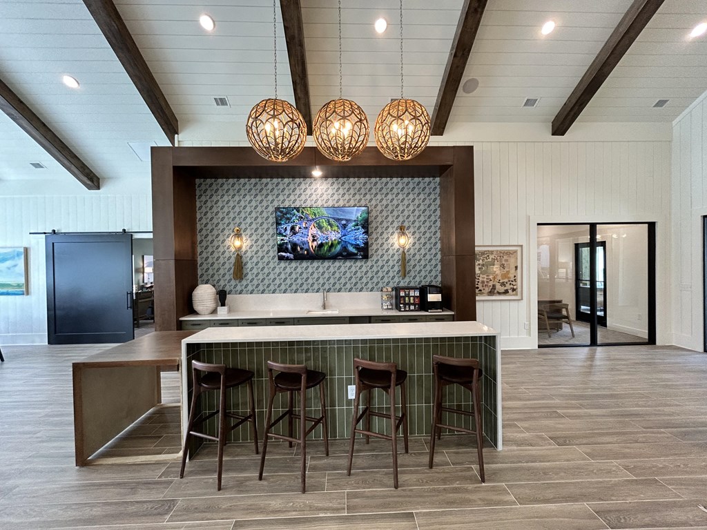 a kitchen with a bar and stools and a tv on the wall