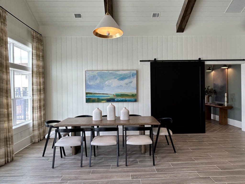 a dining room with a wooden table and chairs and a painting on the wall