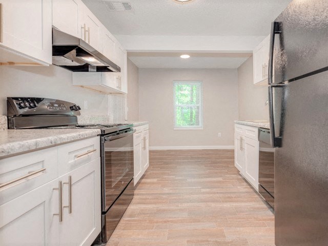 A kitchen with white cabinets and a black refrigerator.