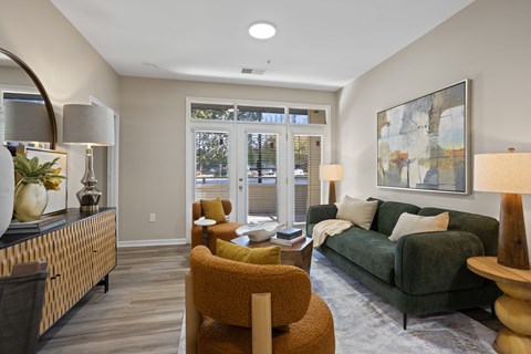 A living room with a green couch, a yellow chair, and a painting on the wall.