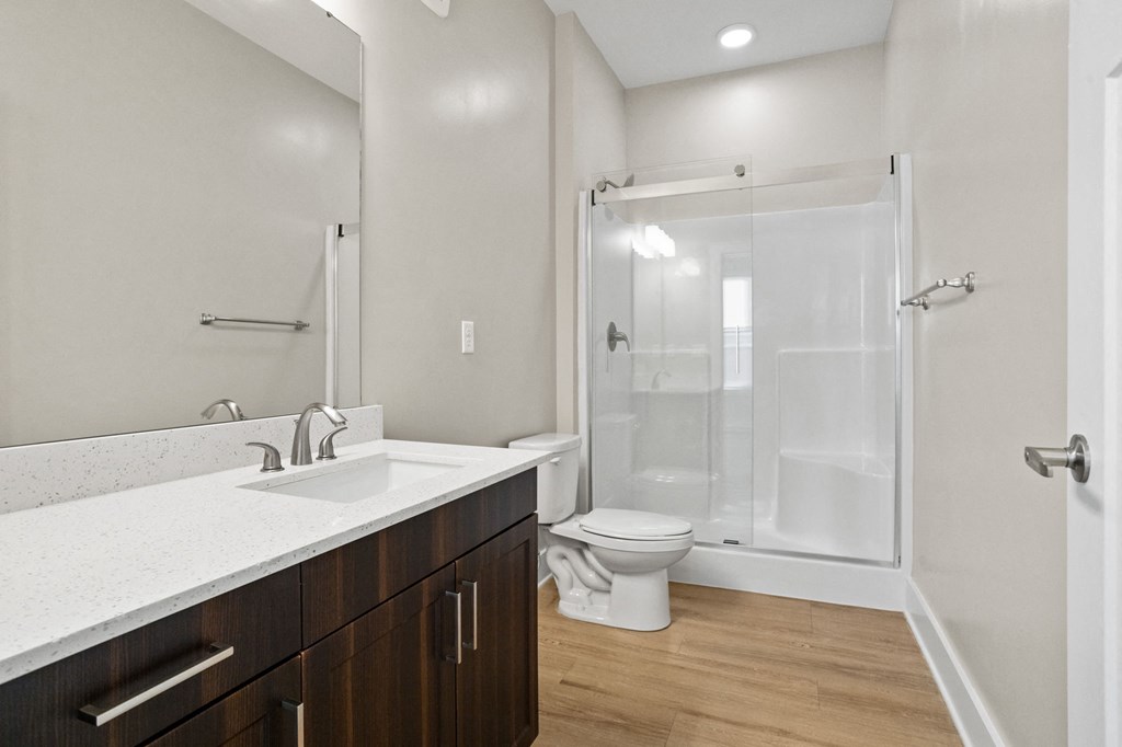 One-Bedroom Luxury Apartments in Greer, SC - Park View Greer - Bathroom Featuring Large Mirror, Dark Cabinetry, and Glass Shower Doors