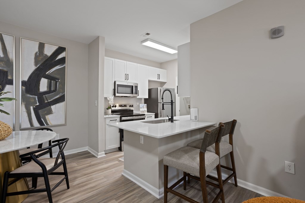 Flatiron West Trade Apartments staged model unit kitchen connected to living room with stainless steel modern appliances and quartz countertops