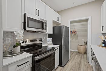 A kitchen with white cabinets and a black fridge.