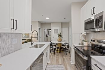 A kitchen with white cabinets and a black stove top oven.