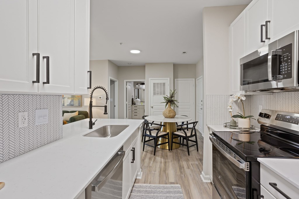 Flatiron West Trade Apartments staged model unit kitchen connected to living room with stainless steel modern appliances and quartz countertops